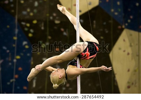 Perm, Russia - April 25, 2015. Championship Perm region at pole sport and dance. blonde in a black swimsuit with a pink pattern makes the element