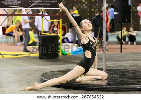 Perm, Russia - April 25, 2015. Championship Perm region at pole sport and dance. Teen girl in a black swimsuit with a gold pattern performs at competitions