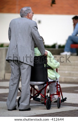 Old man pushes his wife in a wheel chair