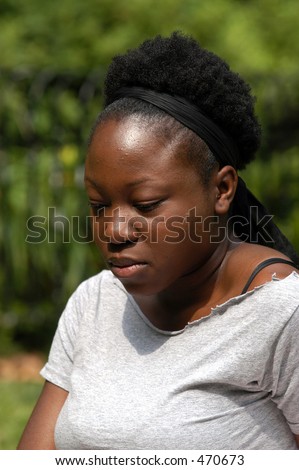 A sad young african american woman sits in the park and thinks.