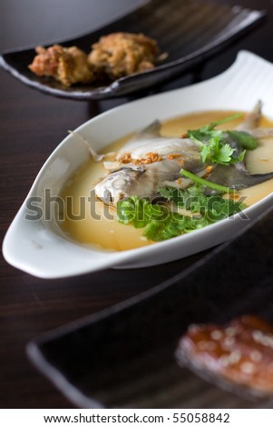 Assorted asian dishes - soft shell crab, steamed pom fret and grilled eel, placed neatly on the table