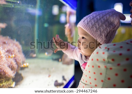 Happy baby watching fishes in aquarium