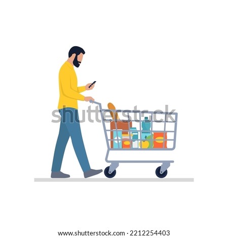 Man doing grocery shopping at the supermarket: he is pushing a shopping cart and using his smartphone, isolated on white background