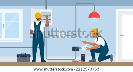 Professional electricians at work, they are checking the electricity box and installing a socket
