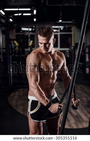 Beautiful sport bodybuilder man on a diet, weight training with dumbbells pumping muscle.With six pack, perfect brakes, shoulders, biceps, triceps and chest.Young adult doing weight lifting at the gym