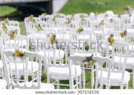 White chairs at a wedding ceremony. Beautiful wedding set up. Luxury Wedding Flower Arrangement. Decorated with flowers at a wedding ceremony outdoors.