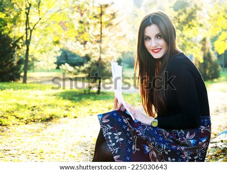 Young brunette girl studying in the park - autumn colors
