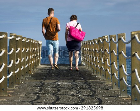 Young couple walking on a ocean pier