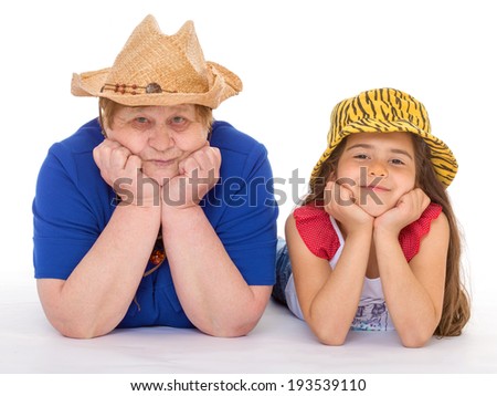 Grandmother and granddaughter lie on the floor in hats
