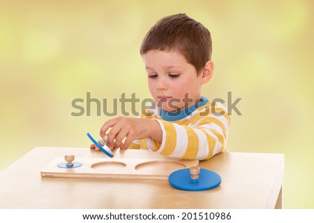 A boy playing at a table with developmental toys.child, happiness and people concept, lovely smiling toddler portrait