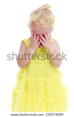 Sad girl in the yellow dress hides his face.Isolated on white background.