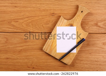 Empty note paper with pen on a wooden cutting board background