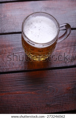 A classic mug full of light beer standing on a wooden table