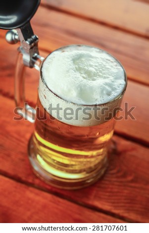 Light beer pouring into a mug standing on a wooden table