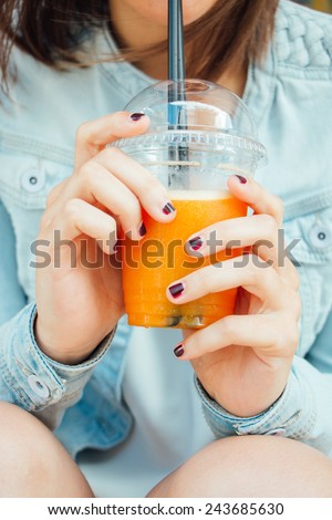 Teen girl hands with nail polished holding  a fruit smoothie