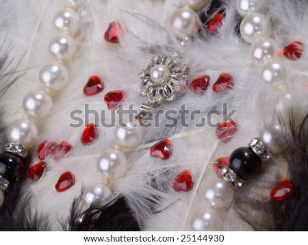 detail of pearl necklace on black and white feathers with strass hearts