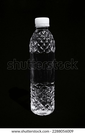 Small beautiful plastic bottle full of water isolated on black. Transparent liquid in a decorative bottle with white cap 商業照片 © 
