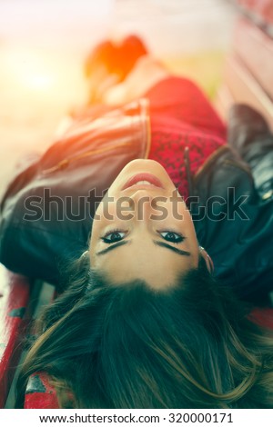 Young girl lying on a bench belly up with sunbeams