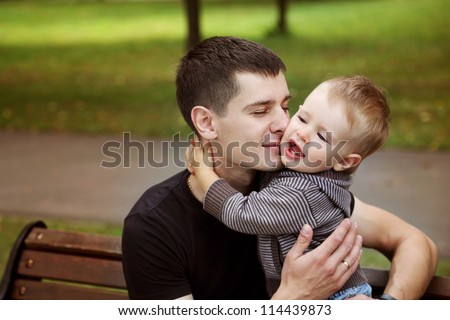 Little son kissing his father  in summer park
