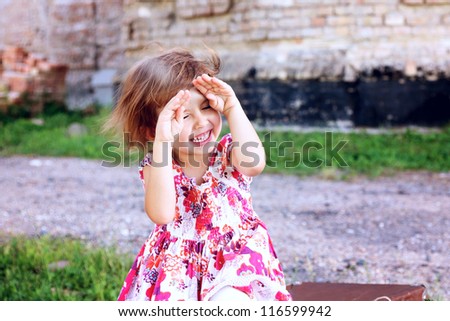 beautiful little girl hides her face in her hands