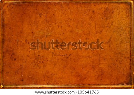 Antique, honey-coloured, leather-bound book cover with gilded banding and tooling . Textured, distressed and marked from ages of use. Grunge background.