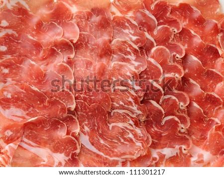 Ham background of thin slices of various Italian dry-cured ham in close-up.
