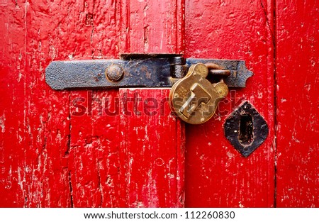 Red, rustic door with closed padlock