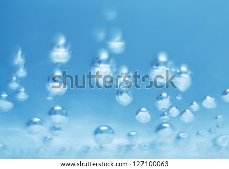 Bubbles of oxygen in glass of water on a blue background. Mineral water. Bubbles of oxygen .Water enriched with oxygen.Oxygen. Water.Water background. Macro.Texture.Glass with water.Natural. Abstract.