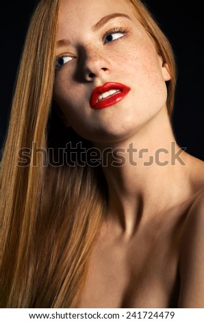 Beauty. Perfect skin .red-haired model with freckles  on a black background in the studio  red lips white teeth woman