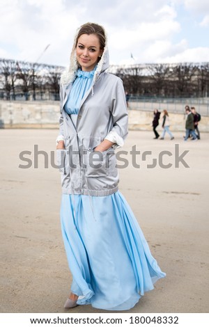 PARIS - MARCH 1, 2014: Stylish European woman with long blue skirt and gray jacket in the Tuileries Garden. Paris Fashion Week: Ready to Wear 2014/2015 is held from February 25 to March 5, 2014.