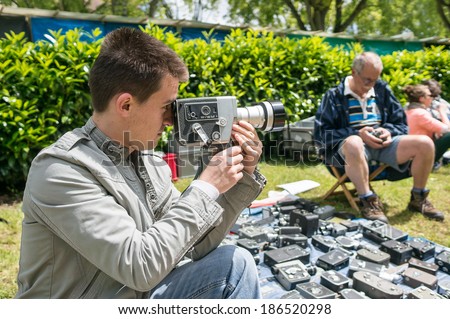 FRANCE, BIEVRES - June 2: Young amateur tries a vintage movie camera in front of a stand. The 50 th Bievres International photofair is held on June 1 & 2 2013 in Bievres, France.