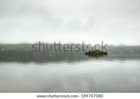 Minimalist Landscape, little island in the lake covered by fogs, Lanobre, Cantal, Auvergne, France