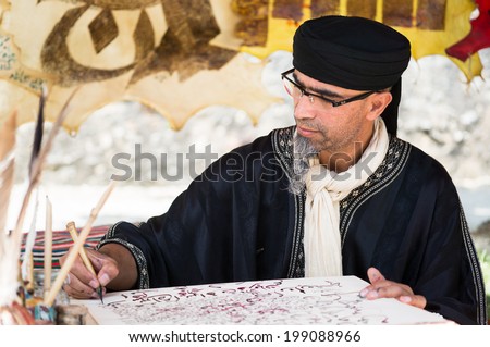 PROVINS, FRANCE - JUNE 15, 2014: Man in old Arabic costume writes on a parchment. The medieval festival is held annually in a weekend of June.