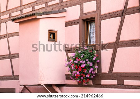 Little wooden window decorated by flowers on a timber frame wall, Eguisheim, Alsace, France