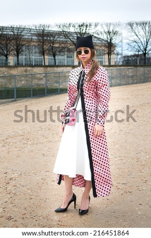 PARIS - MARCH 1, 2014: Stylish Asian woman with pink trench coat with black spots in the Tuileries Garden. Paris is one of the capitals of fashion in the world.