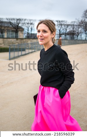 PARIS - MARCH 1, 2014: Stylish European woman with pink skirt and black high heels in the Tuileries Garden. Paris Fashion Week: Ready to Wear 2014/2015 is held from February 25 to March 5, 2014.