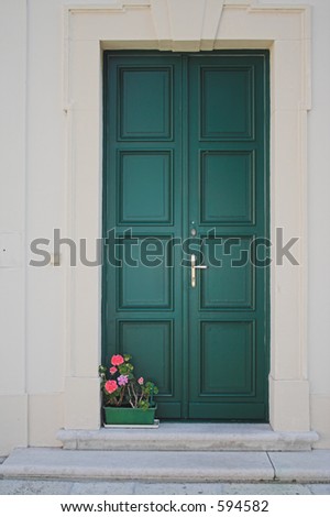 Red flowers on door step of a closed green door