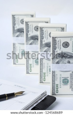 Fountain pen on diary and bundles of US paper currency