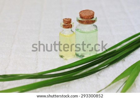 natural herbal essential oil in bottle with fresh green leaves on white towel bathroom spa treatment set for beauty care