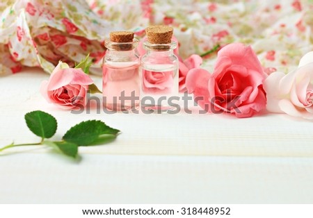 Fresh organic rose water eco beauty treatment flowers bottles wooden backdrop pink creamy tones shallow DOF