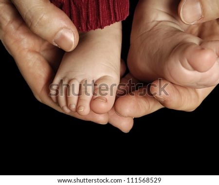Closeup of the feet of a baby and his  dad \'s hands