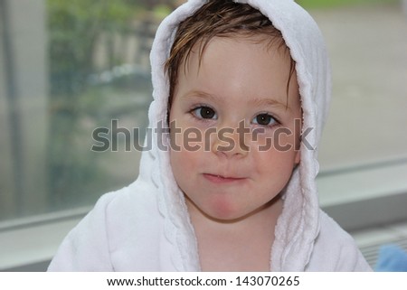 Little girl (one year and six months of age) in a white robe after a swimming pool