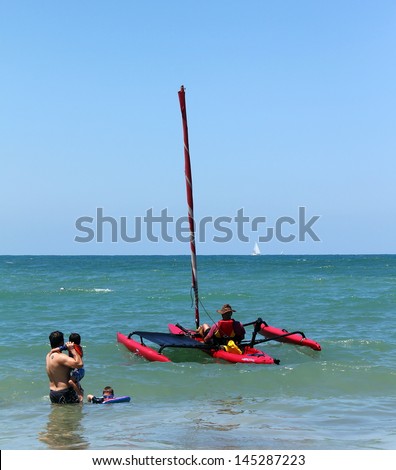 TEL AVIV, ISRAEL - JULY 06: Small trimaran with sail preparing to go to sea in the hot summer day on the beach of Tel Baruch, one of best  for vacation and sports on July 06, 2013 in Tel Aviv, Israel.