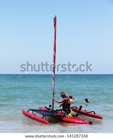 TEL AVIV, ISRAEL - JULY 06: Small trimaran with sail preparing to go to sea in the hot summer day on the beach of Tel Baruch, one of best  for vacation and sports on July 06, 2013 in Tel Aviv, Israel.