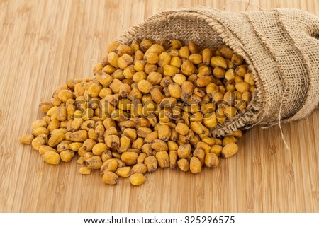 Roasted salted corn nut pour from brown textured sack