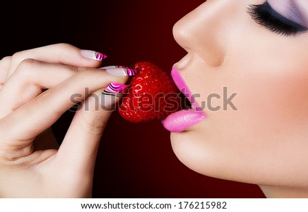 Beautiful girl with pink nails eating strawberry