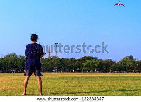 Young man flying a kite at Royal Plaza Park (Sanam Luang Park) in Bangkok.