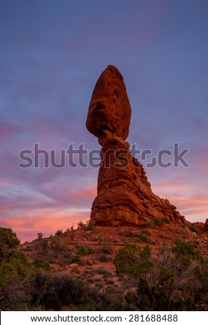 Vibrant pink sunset colours behind the Balanced Rock in Utah