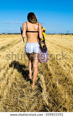Young women goes on a field in rural areas with a bag