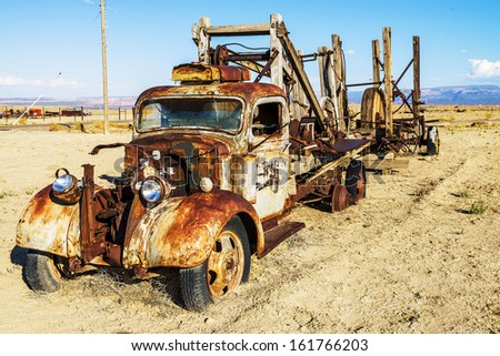 vintage truck abandoned and rusting away in the desert, ghost town in the background